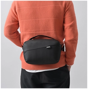 Men's matte black waterproof chest bag shown on model with focus on sport design label