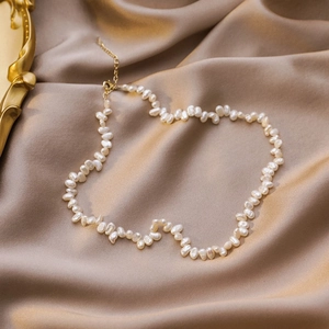 Vintage baroque irregular pearl necklace with gold clasp on champagne silk background