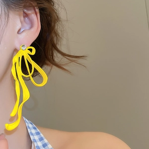 Close-up of bright yellow ribbon bow earrings with sparkling zircon on model