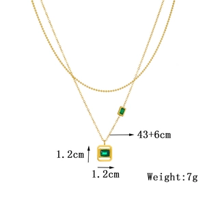 Detail of gold-plated double chain necklace with green square stone pendant and specs