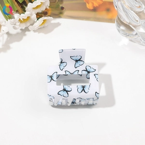Close-up of white acrylic hair claw clip featuring elegant blue butterfly patterns