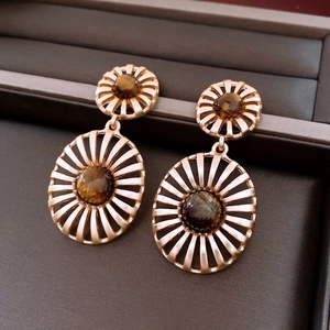 Macro shot of vintage hollow sunburst gold earrings with oval tiger eye stones in jewelry box
