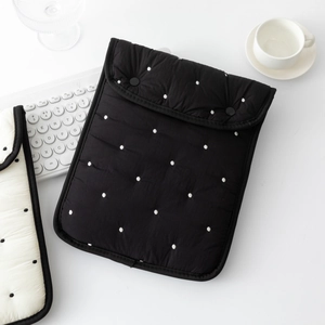 Detailed view of black polka dot quilted sleeve with double button closure for tablet