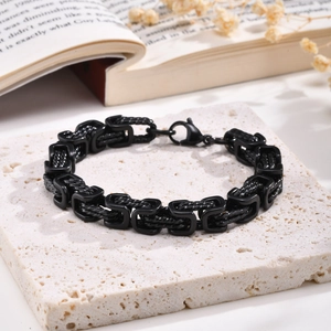 Detail view of a black stainless steel woven Byzantine chain bracelet on a white stone