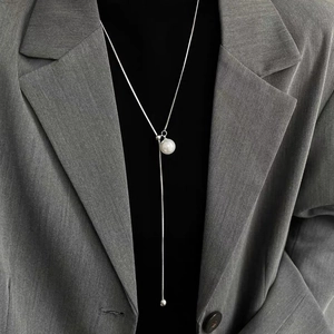 Elegant Y-shaped long pearl necklace with silver chain over a black turtleneck sweater