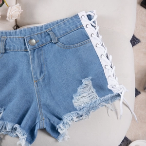 Dettaglio degli shorts in denim azzurro con lacci laterali incrociati e bordi strappati