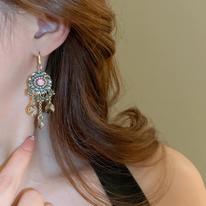Close-up of bohemian tassel earrings with colorful crystals worn by a model
