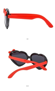 Detail view of heart-shaped sunglasses with iconic red bow and polished red temples