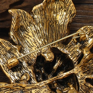 Macro shot of gold floral brooch back showing vintage brushed texture and secure safety pin clasp