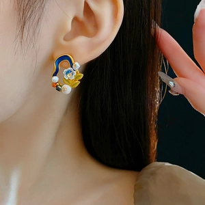 Detailed close-up of vintage flower stud earring with blue enamel and pearls on ear