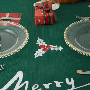 Green Christmas tablecloth with holly patterns and Merry text for holiday table decor