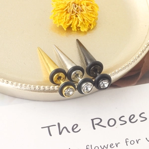 Detailed view of silver, gold, and black spiked stud earrings with crystals on a jewelry tray