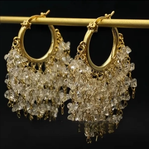 Macro shot of elegant gold hoop earrings with cascading clear crystal tassel details