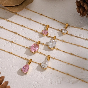 Minimalist gold necklaces with oval teardrop and round zircon stones on white background
