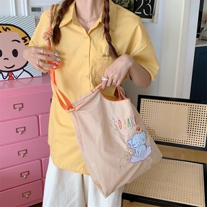 Detail of beige Oxford tote bag featuring cute blue elephant embroidery and orange straps