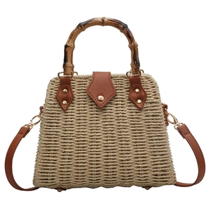 Retro straw handbag with bamboo handle and brown leather patch, front view on white background