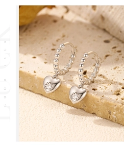Detail of s925 silver beaded hoop earring with heart pendant and star-set zircon