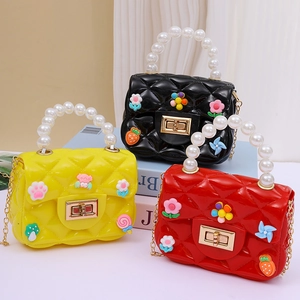 Mini jelly crossbody bags with pearl handles and cartoon charms in yellow, black, and red