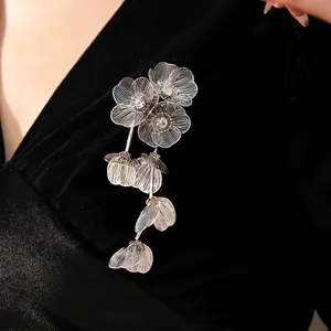 Silver hollow floral brooch with tassels and rhinestones on black velvet fabric