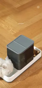Macro view of automatic pet feeder and waterer set with a white cat drinking water