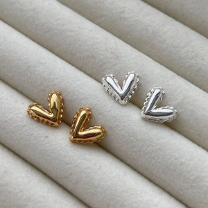 Balloon heart stud earrings in polished gold and silver on a jewelry display tray