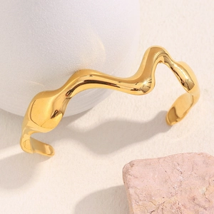 Detail shot of a minimalist 18K gold-plated wave cuff on a decorative white stone