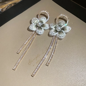Détail de boucles d'oreilles fleur brodée avec glands en zircon et perles sur cuir