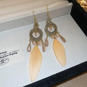 Detailed shot of Bohemian long orange feather earrings in a gold hollow ring design