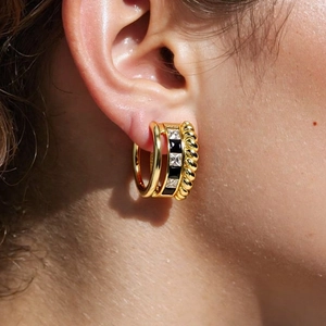 Macro shot of gold-plated layered earrings with black enamel and white zircon inlay