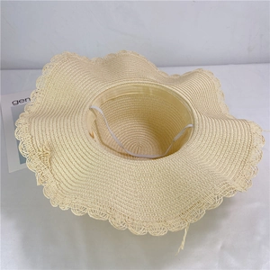 Beige straw sun hat with wavy brim and windproof strap for beach wear and summer sun protection