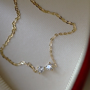 Macro shot of gold bow pendant with heart-shaped zircon stones and delicate O-chain