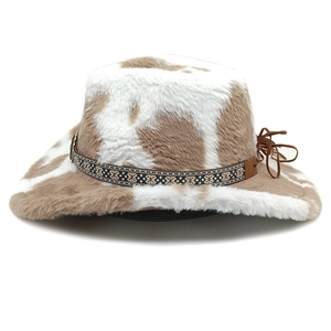 Détail de la texture en peluche à motif vache et de la bande tissée ethnique sur le chapeau cowboy
