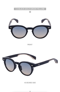 Detail of oval black sunglasses with gradient lenses and golden arrow rivet accents