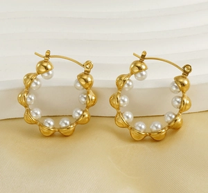 Détail de boucles d'oreilles créoles dorées 18k avec perles blanches sur soie