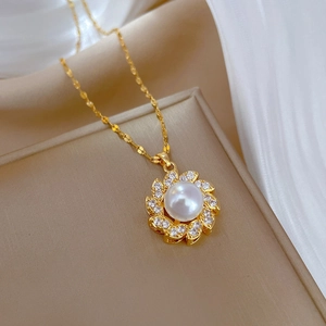 Dettaglio del pendente a girasole con perla e diamanti su catena in acciaio al titanio oro