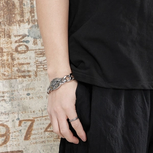 Detail of vintage silver skull bracelet with chunky chain and round embossed pendant