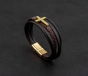 Macro view of dark brown leather braided bracelet with golden cross and magnetic clasp