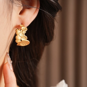 Vue détaillée de boucles d'oreilles dorées en forme de C avec texture martelée sur mannequin