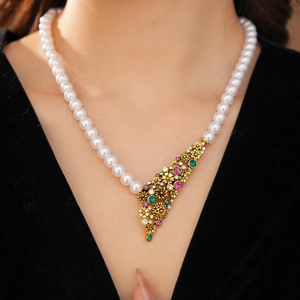 Détail d'un collier de perles vintage avec pierres colorées porté par un mannequin chic