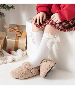 Détail de chaussettes hautes blanches à nœud et chaussures en peluche kaki à boucle