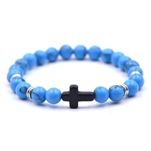 Close-up of blue turquoise beads with black matte cross charm and silver spacers