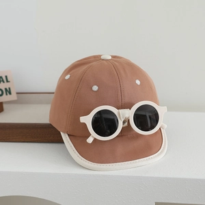 Détail de la casquette marron pour bébé avec accessoire lunettes blanches et coton doux