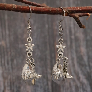 Détail de boucles d'oreilles western argentées avec chapeau de cow-boy, botte et étoile