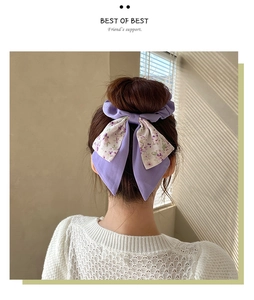 Detail of a purple floral bow hair tie with long ribbons on a model back bun hairstyle