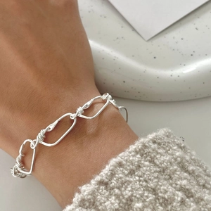Detail of a minimalist 925 silver braided chain bracelet with twisted metal textures
