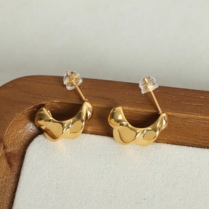Polished 18K gold plated C-shaped geometric hoop earrings on a soft jewelry display