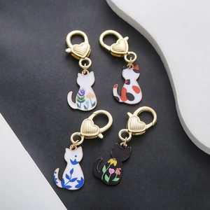Detail of four colorful enamel cat charms with heart-shaped golden lobster clasps