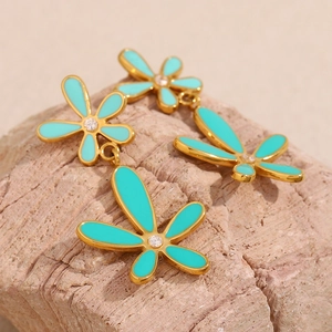 Detail of green floral earrings with 18K gold plating and center zircon on stone background