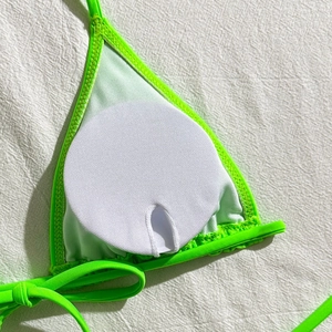 Detail of removable round white chest pads inside the lime green mesh bikini top