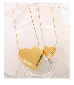 Macro view of gold heart pendants on snake chains showing mirror polished surface
